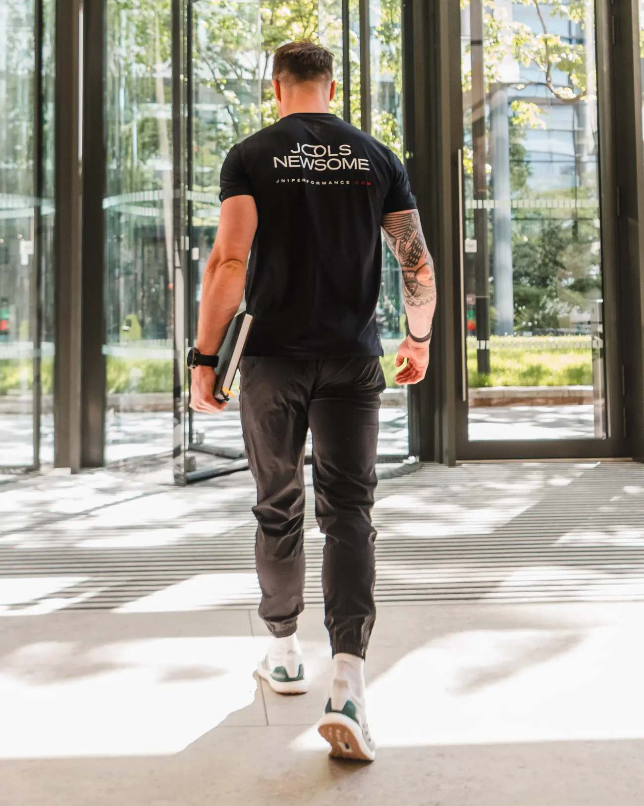 Jools Newsome walking into a City office building in his JN1 Performance training top.